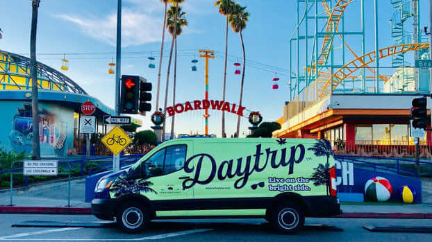the green daytrip team sprinter van parked in front of the santa monica pier
