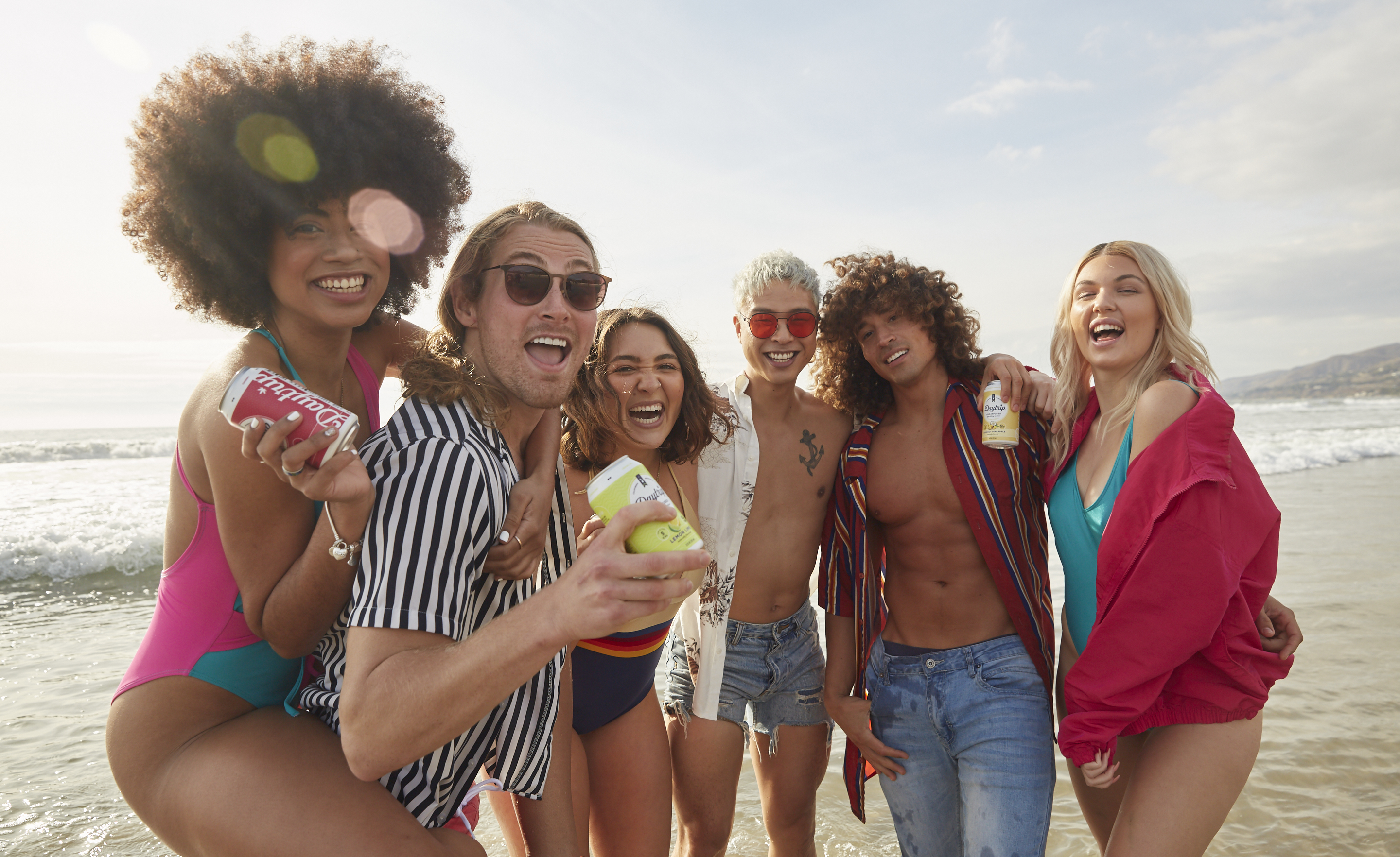 group photo of stylish young people holding cans of daytrip sparkling water on a los angeles beach