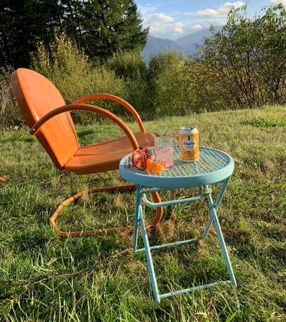 daytrip cbd infused sparkling water sitting on a side table next to an outdoor lounge chair on grass