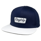 California Snapback hat on a white background. Navy blue / denim upper hat with a white "california made" Daytrip logo patch with blue embroidered stitching. White brim on hat.