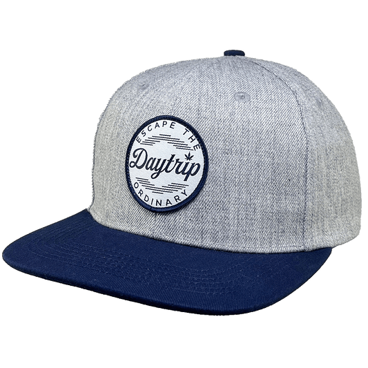Daytrip Escape the Ordinary snapback cap in heather grey with navy bill and round Daytrip Escape The Ordinary woven patch