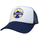 Front view of the Daytrip mountain trucker hat. Navy blue brim and mesh back, with a white front. On the white front is a circular lockup featuring the Daytrip script logo laid over top of a blue and yellow mountain scene, with a highway vanishing in the 